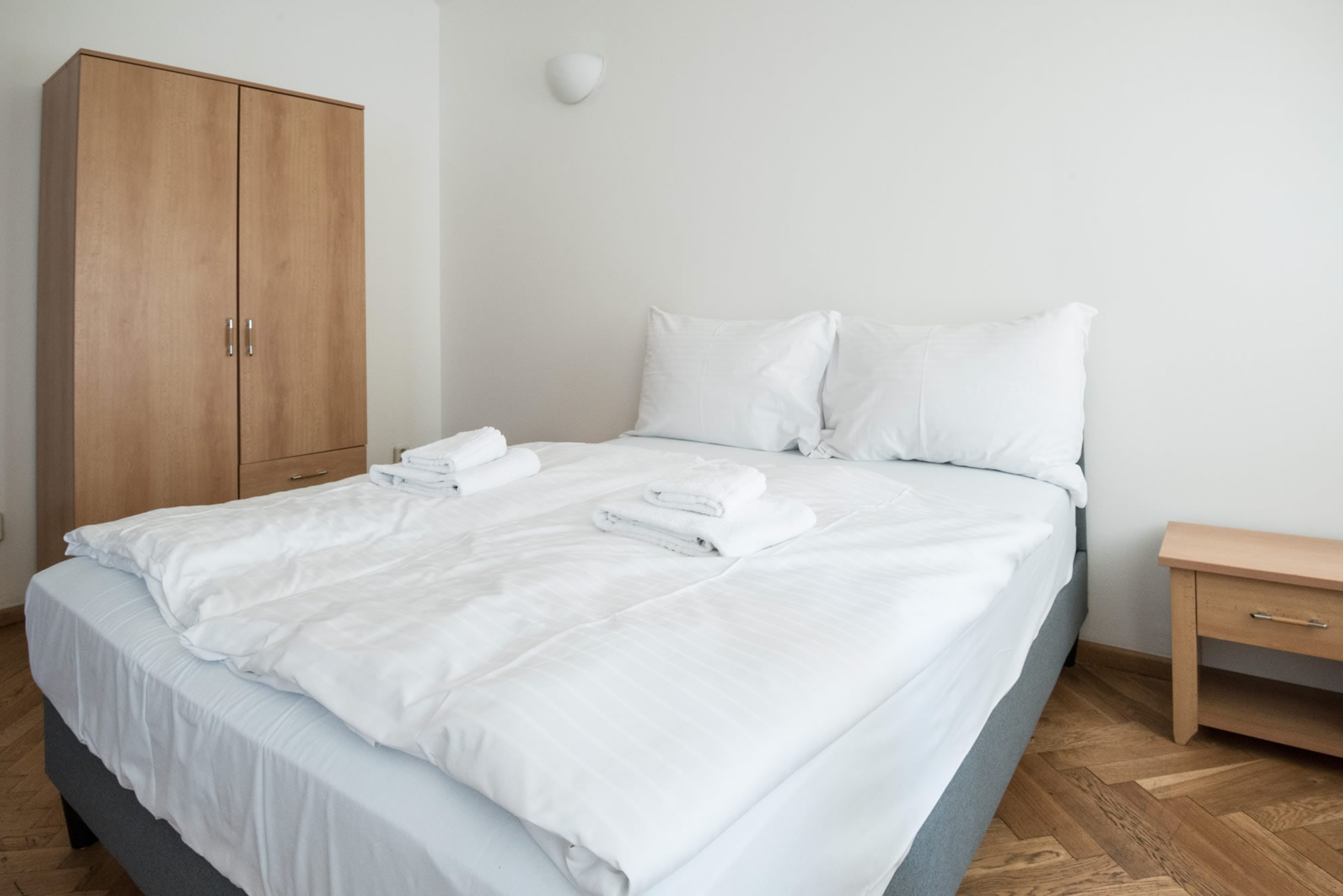 Double bed with white bed sheets in a bright apartment studio