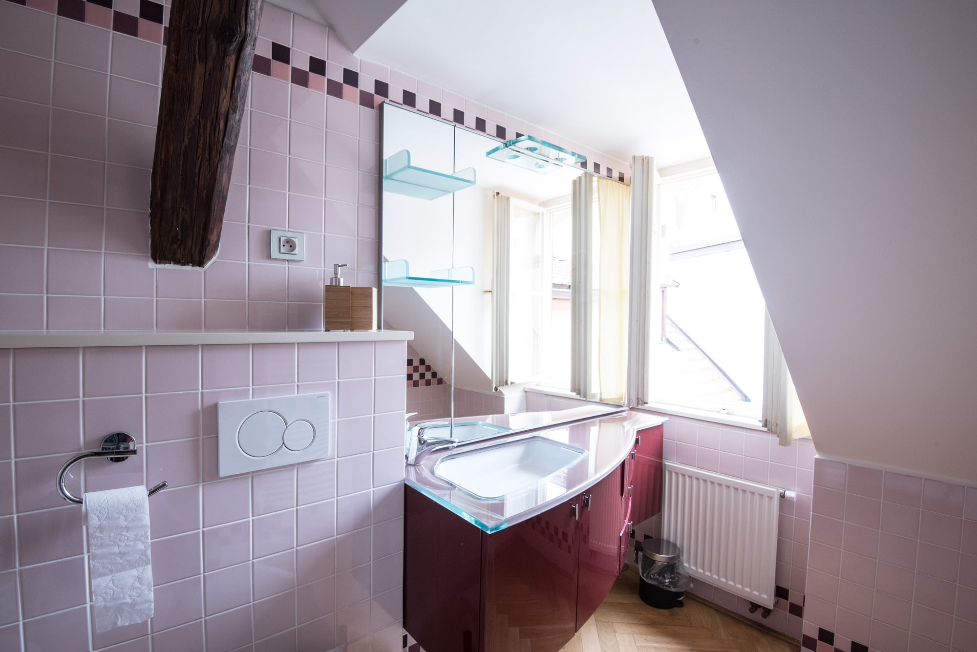 Bathroom covered with pink tiles. A mirror on the wall.