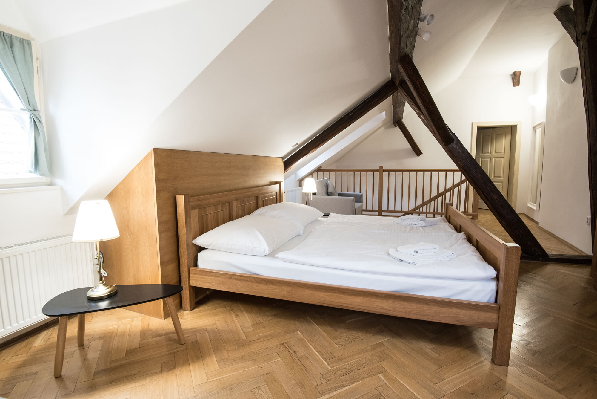 Attic bedroom with wooden parquet, wood beams and a double bed